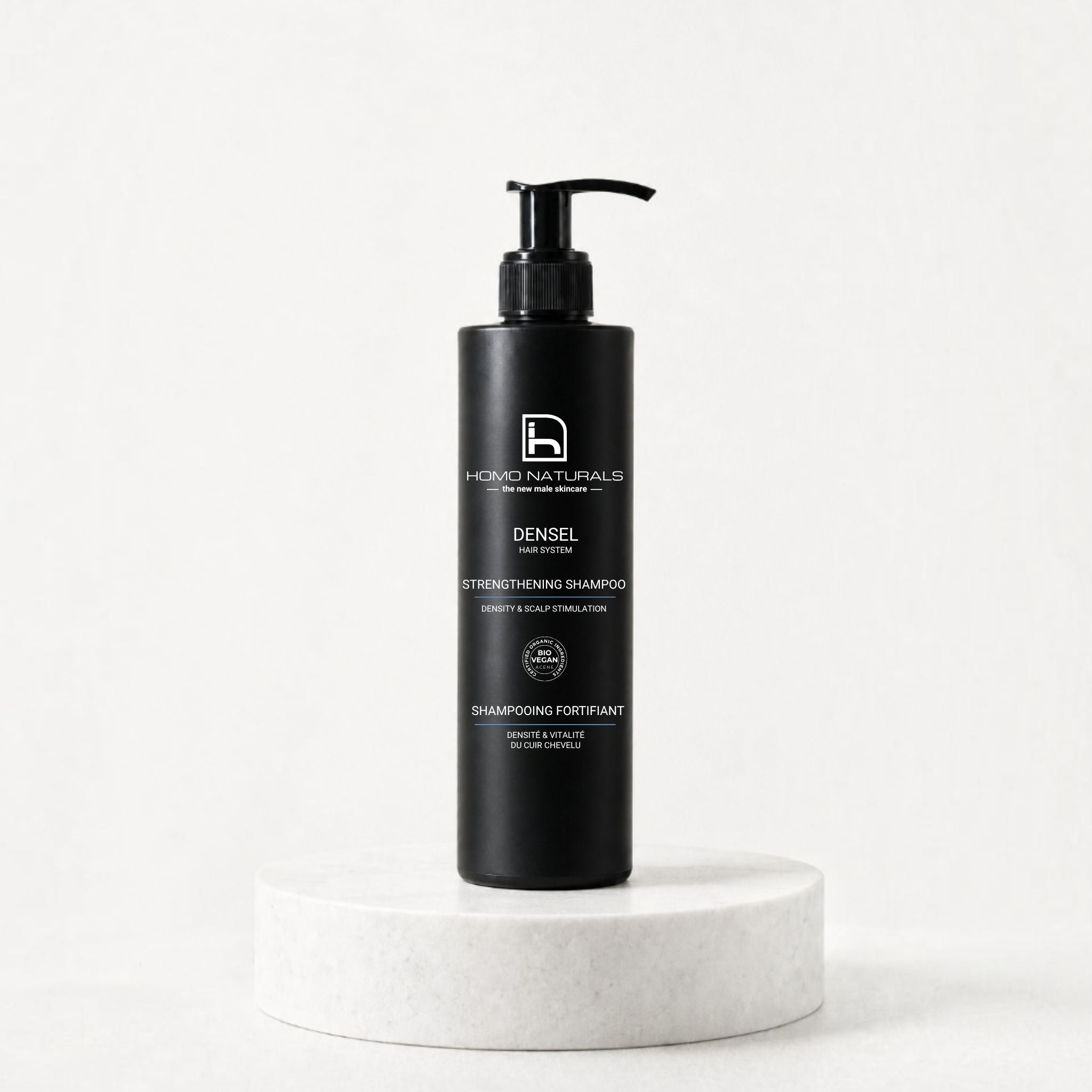 Botella de DENSEL Hair System Shampoo presentada sobre un pedestal para el cuidado capilar masculino. Champú anticaída natural para hombre. Con certificación Bio + Vegan.