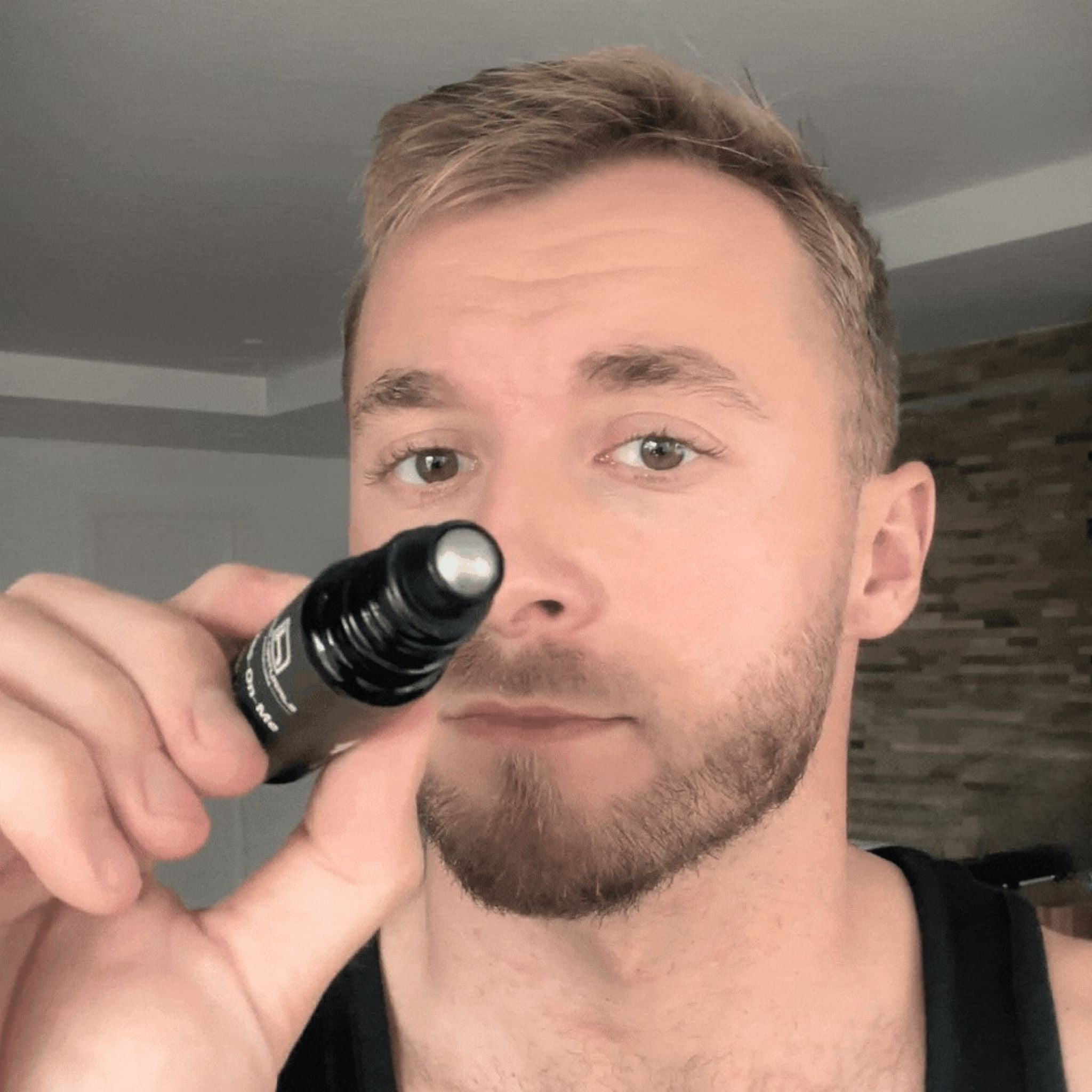 Hombre mostrando Eyes-On-Me de Homo Naturals con aplicador roll-on metálico diseñado para aportar una sensación refrescante en el contorno de los ojos. Contiene un tratamiento integral contra bolsas, ojeras y arrugas del contorno de ojos. Producto natural con certificación bio + vegan. Con cafeína. Con ácido hialurónico. Con extracto de pepino. Sin derivados del petróleo, sin parabenos.